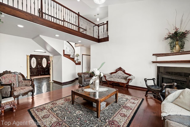 13205 Van Pamel Dr, Shelby Twp, MI 48315 - living area with stairs, wood finished floors, arched walkways, a glass covered fireplace, and a towering ceiling