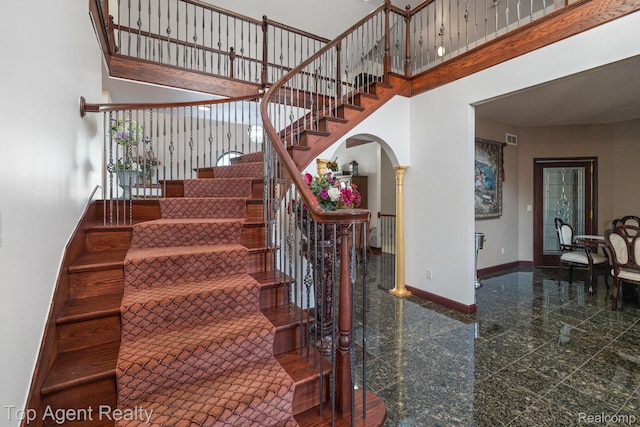 13205 Van Pamel Dr, Shelby Twp, MI 48315 - staircase featuring granite floors, arched walkways, and a high ceiling