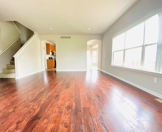 1924 Savannah Ln, Ypsilanti, MI 48198 - unfurnished living room featuring arched walkways, dark wood-style floors, and stairway