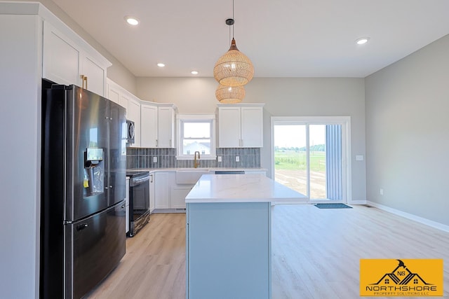3973 W Harrison Rd, Hart, MI 49420 - kitchen with stainless steel fridge, black range with electric cooktop, light wood-style floors, decorative backsplash, and a kitchen island