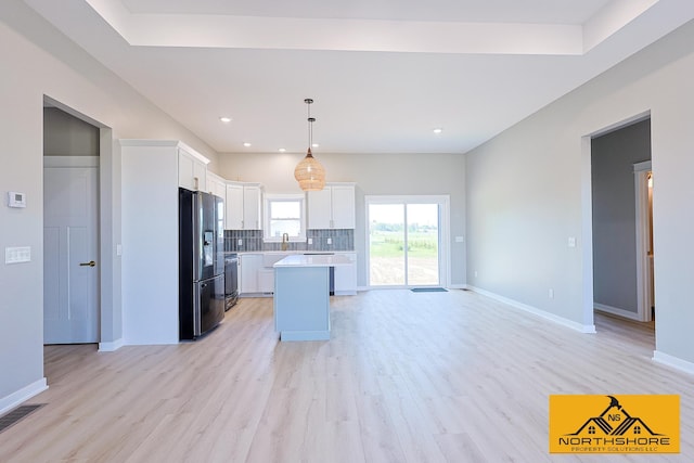 3973 W Harrison Rd, Hart, MI 49420 - kitchen featuring stainless steel fridge with ice dispenser, light countertops, white cabinetry, tasteful backsplash, and light wood-style floors