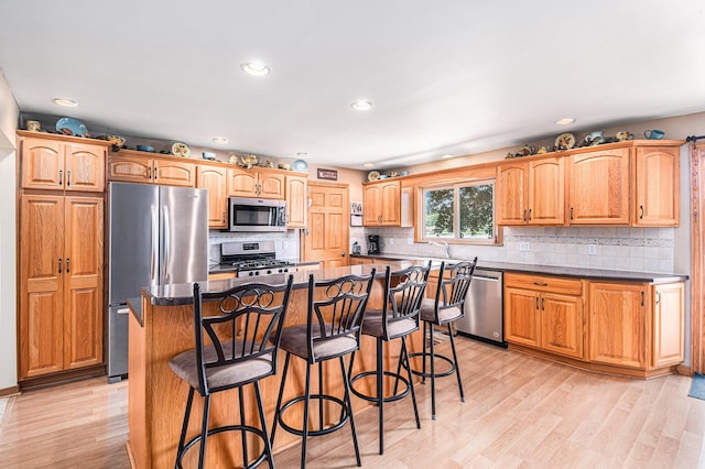13278 W Stanton Rd, Trufant, MI 49347 - kitchen with appliances with stainless steel finishes, dark countertops, a kitchen bar, decorative backsplash, and recessed lighting