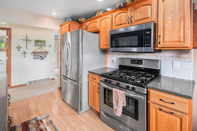 13278 W Stanton Rd, Trufant, MI 49347 - kitchen featuring stainless steel appliances, light wood-style flooring, decorative backsplash, dark stone countertops, and recessed lighting