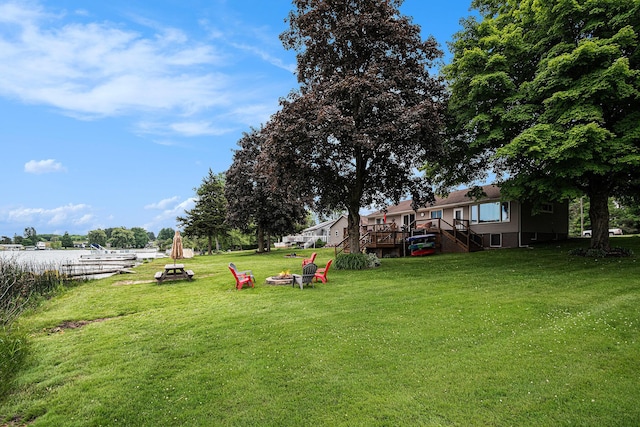 13278 W Stanton Rd, Trufant, MI 49347 - view of grassy yard with a fire pit, a deck with water view, and stairs