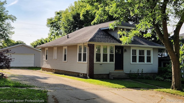 1020 N Monroe St, Lapeer, MI 48446 - bungalow-style house with entry steps, an outbuilding, a detached garage, and roof with shingles
