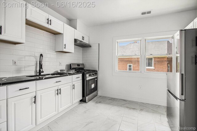 2701 Tuxedo St, Detroit, MI 48206 - kitchen with stainless steel appliances, under cabinet range hood, light marble finish flooring, decorative backsplash, and white cabinetry