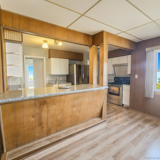 13513 Chestnut St, Southgate, MI 48195 - kitchen featuring appliances with stainless steel finishes, light stone counters, white cabinetry, light wood finished floors, and a peninsula