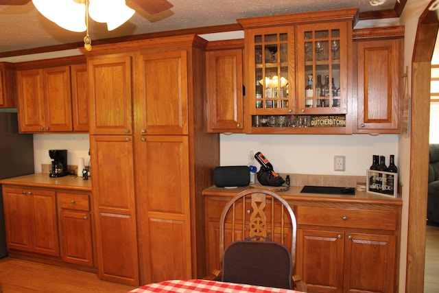 143 Tree Stand Rd, Rose City, MI 48654 - kitchen featuring brown cabinets, light countertops, light wood-type flooring, a ceiling fan, and a textured ceiling