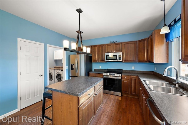 1978 Frances Way, Ypsilanti, MI 48198 - kitchen featuring stainless steel appliances, washer and dryer, dark countertops, dark wood-type flooring, and hanging light fixtures