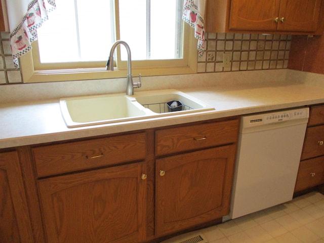 507 Mackinaw St, Durand, MI 48429 - kitchen with dishwasher, brown cabinetry, light countertops, and backsplash
