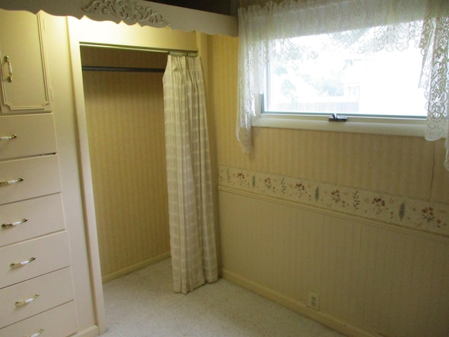 507 Mackinaw St, Durand, MI 48429 - unfurnished bedroom featuring a closet, wallpapered walls, light colored carpet, and a wainscoted wall