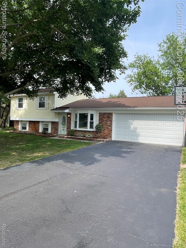 3834 Tara Dr, Highland, MI 48356 - split level home with driveway, an attached garage, a front lawn, and brick siding