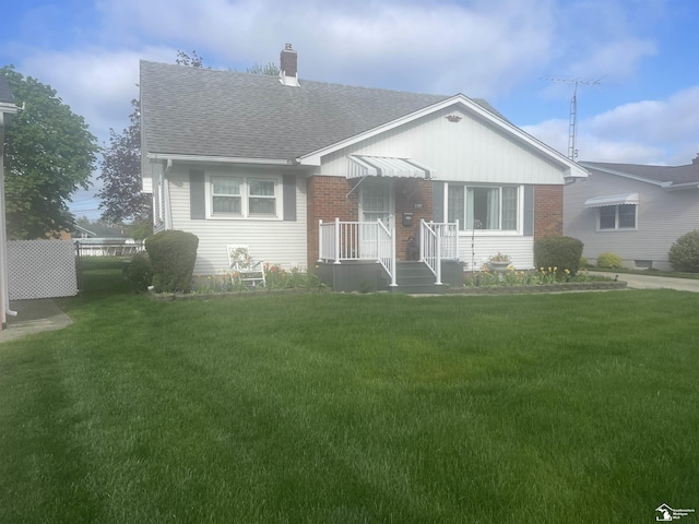 1107 Mccormick St, Monroe, MI 48162 - bungalow-style home featuring a shingled roof, a front lawn, a chimney, and brick siding