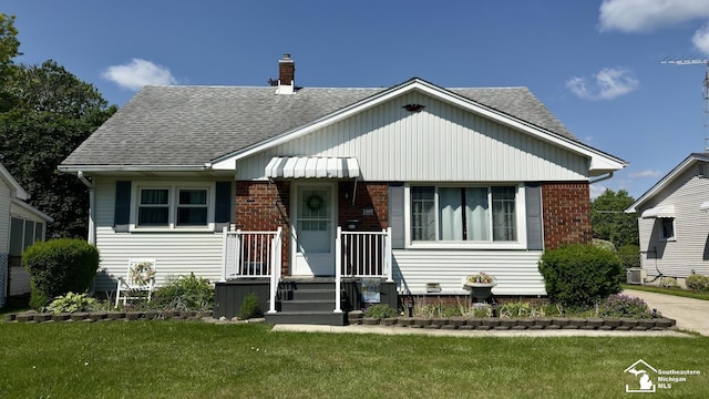 1107 Mccormick St, Monroe, MI 48162 - bungalow featuring a shingled roof, a front yard, a chimney, and brick siding