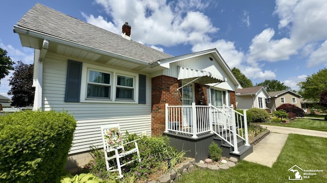 1107 Mccormick St, Monroe, MI 48162 - view of side of property with brick siding, a chimney, a shingled roof, and a lawn