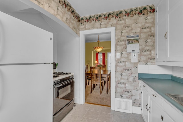 741 Lawrence St, Jackson, MI 49203 - kitchen with white appliances, white cabinets, light tile patterned floors, dark countertops, and light colored carpet
