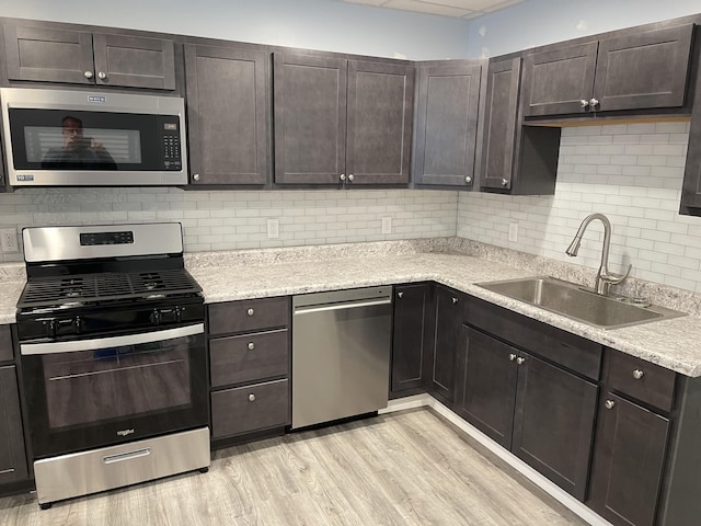 251 Page St NE, Grand Rapids, MI 49505 - kitchen with stainless steel appliances, light wood-type flooring, dark brown cabinets, and backsplash