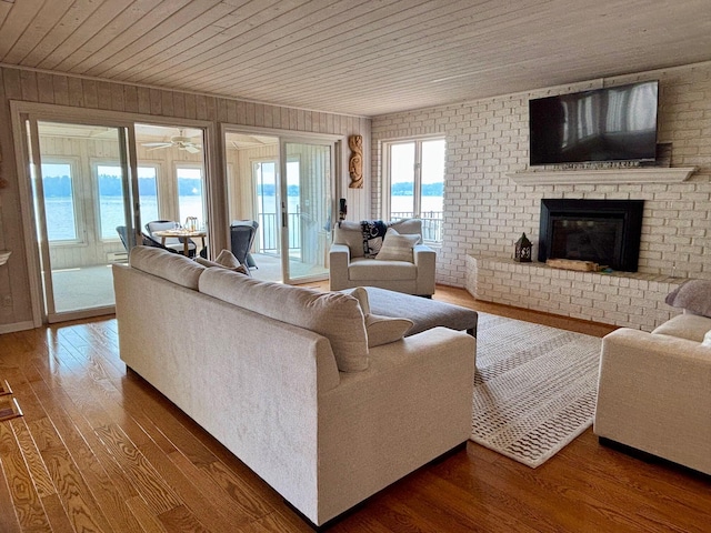 68121 Edgewater Beach Rd, White Pigeon, MI 49099 - living area featuring wood ceiling, wood finished floors, a brick fireplace, wood walls, and a ceiling fan