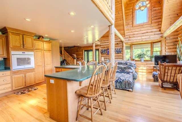 7111 Gilbert Rd, Pittsford, MI 49271 - kitchen with oven, rustic walls, dark countertops, a breakfast bar area, and light wood finished floors