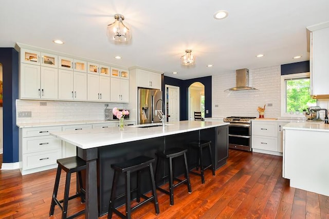 5284 Green Pine Ln, Kalamazoo, MI 49009 - kitchen with stainless steel appliances, ventilation hood, arched walkways, backsplash, and light countertops