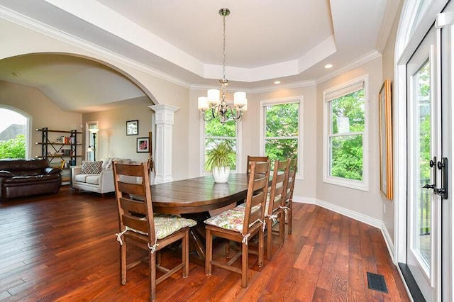 5284 Green Pine Ln, Kalamazoo, MI 49009 - dining space with a chandelier, arched walkways, a raised ceiling, dark wood finished floors, and decorative columns