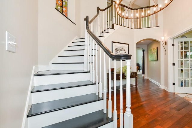 5284 Green Pine Ln, Kalamazoo, MI 49009 - stairs featuring arched walkways, wood finished floors, a high ceiling, and a chandelier