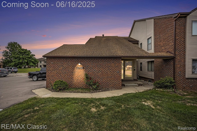 6700 Ridgefield Cir Unit 201, West Bloomfield, MI 48322 - property exterior at dusk featuring brick siding, a yard, a shingled roof, and entry steps
