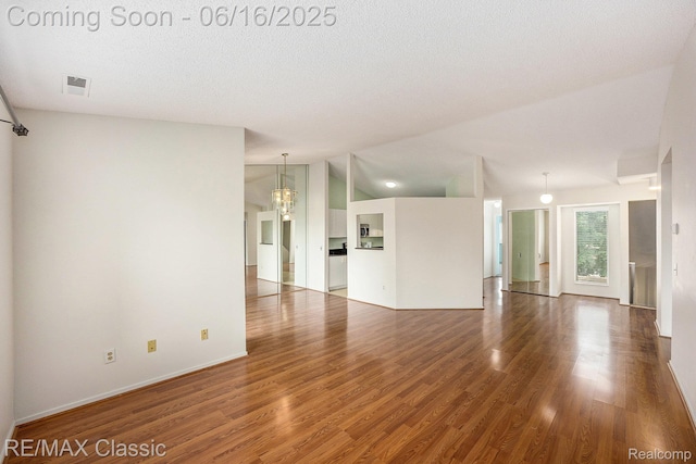 6700 Ridgefield Cir Unit 201, West Bloomfield, MI 48322 - unfurnished living room featuring wood finished floors, lofted ceiling, and a chandelier
