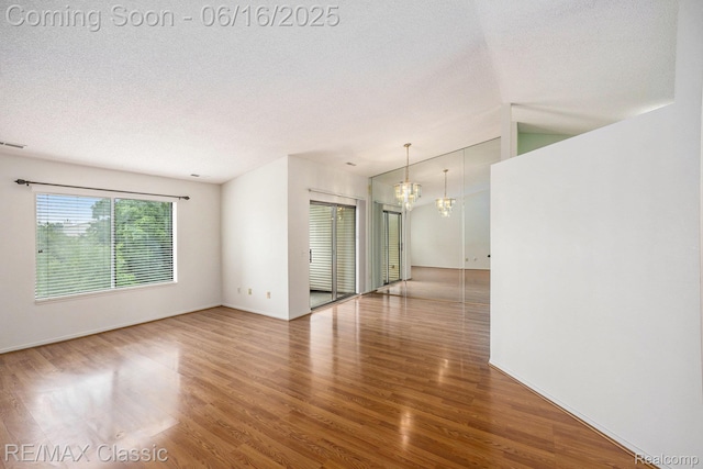 6700 Ridgefield Cir Unit 201, West Bloomfield, MI 48322 - spare room featuring wood finished floors, a chandelier, a textured ceiling, and lofted ceiling