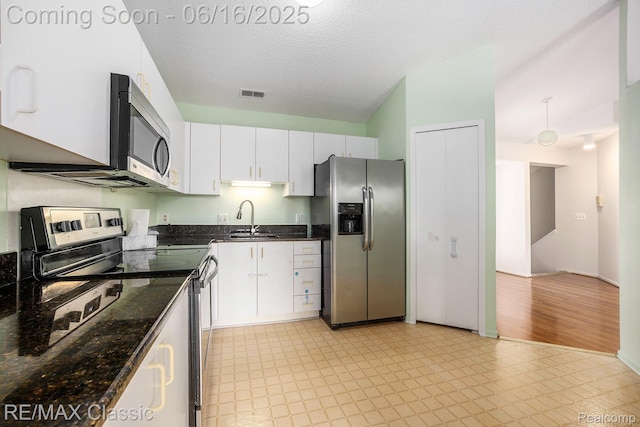 6700 Ridgefield Cir Unit 201, West Bloomfield, MI 48322 - kitchen with appliances with stainless steel finishes, white cabinetry, dark stone counters, light floors, and a textured ceiling