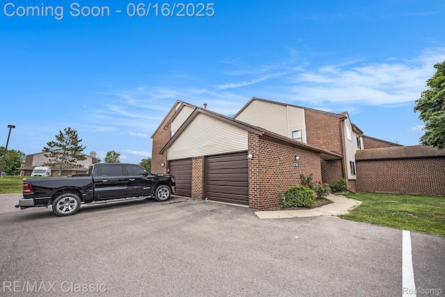 6700 Ridgefield Cir Unit 201, West Bloomfield, MI 48322 - view of property exterior featuring brick siding, an attached garage, and driveway