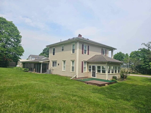 20051 Capital Ave NE, Battle Creek, MI 49017 - rear view of house with a sunroom, a lawn, a chimney, and a deck