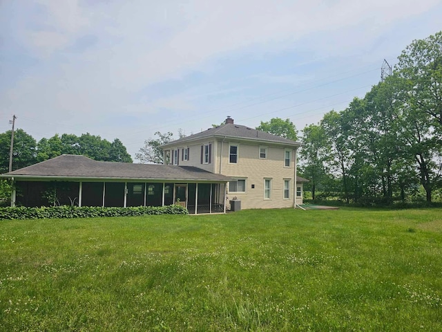 20051 Capital Ave NE, Battle Creek, MI 49017 - rear view of property featuring a sunroom, a yard, and a chimney