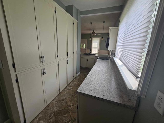 20051 Capital Ave NE, Battle Creek, MI 49017 - kitchen with white cabinets, ceiling fan, stone tile flooring, and a peninsula