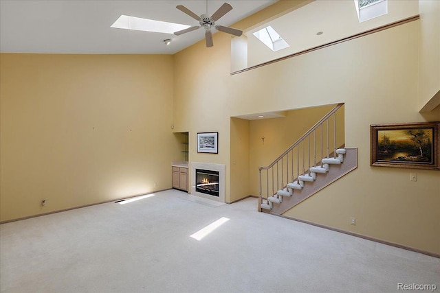 55728 Lorraine Dr Unit 20, Utica, MI 48316 - unfurnished living room featuring a skylight, high vaulted ceiling, light colored carpet, a fireplace with flush hearth, and stairs