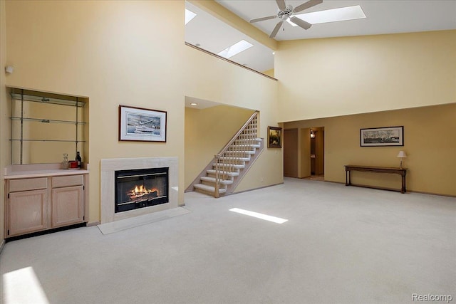 55728 Lorraine Dr Unit 20, Utica, MI 48316 - unfurnished living room with a skylight, stairs, a fireplace, a ceiling fan, and light colored carpet