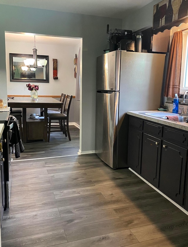 4236 Marianne Dr, Flushing, MI 48433 - kitchen with dark cabinets, freestanding refrigerator, dark wood-style floors, a chandelier, and light countertops