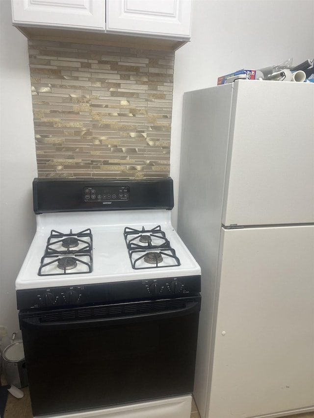 1021 2nd St, Flint, MI 48503 - kitchen with range with gas cooktop, freestanding refrigerator, tasteful backsplash, and white cabinets