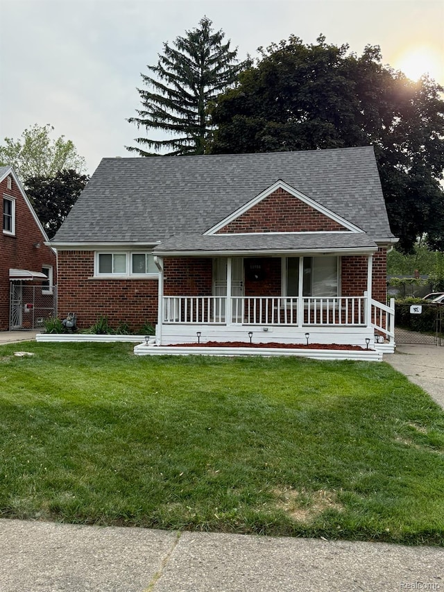 11735 Braile St, Detroit, MI 48228 - view of front facade with brick siding, a front lawn, a shingled roof, and a porch