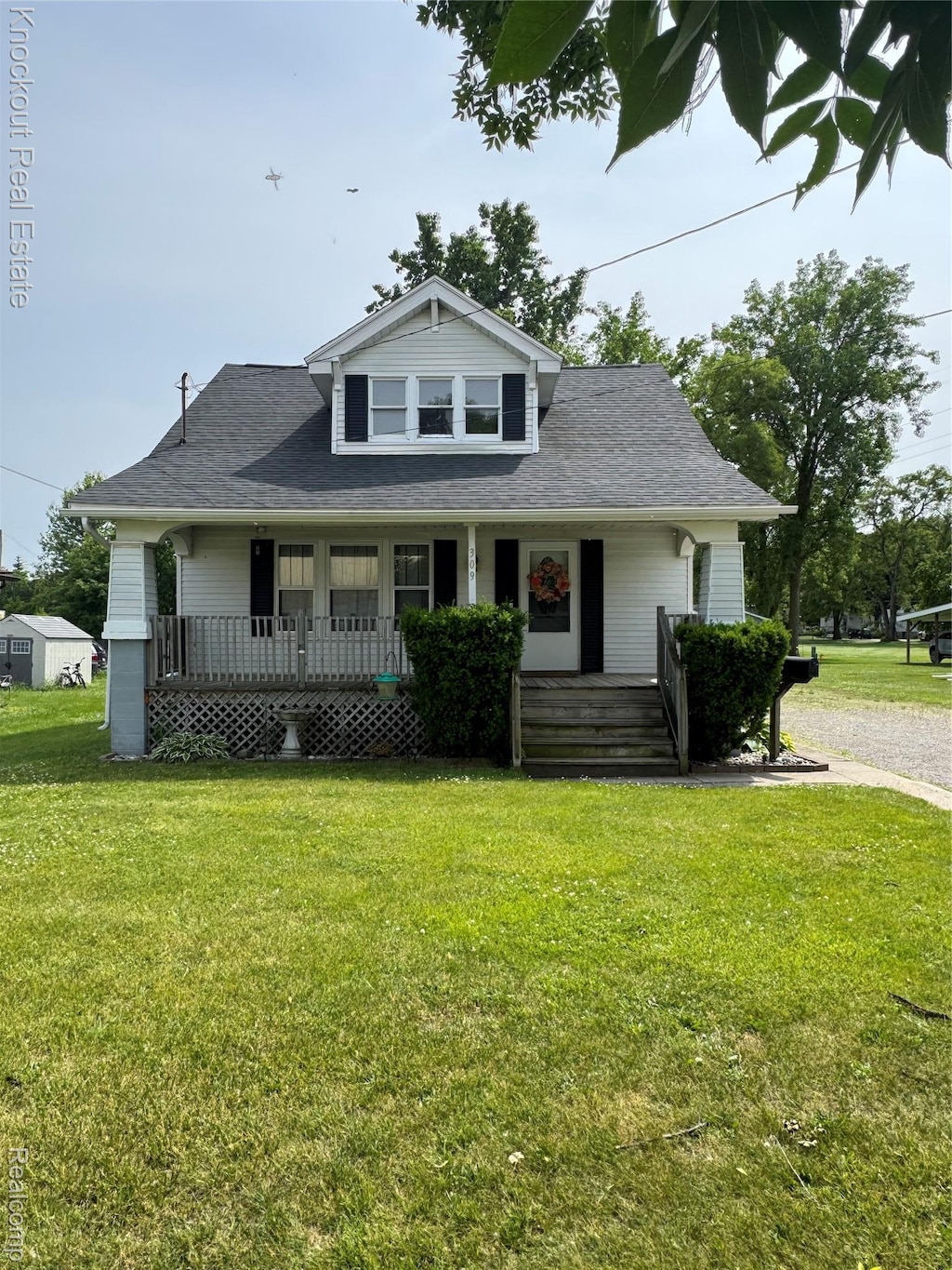 309 Ellsworth St, Saginaw, MI 48604 - bungalow-style home with a porch, a front lawn, and roof with shingles