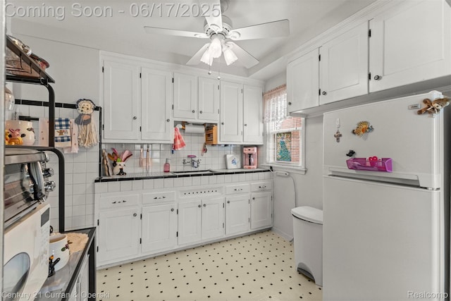 7652 Osage Ave, Allen Park, MI 48101 - kitchen with freestanding refrigerator, white cabinetry, ceiling fan, and tile countertops