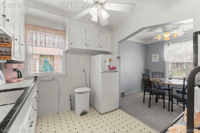 7652 Osage Ave, Allen Park, MI 48101 - kitchen with a ceiling fan, freestanding refrigerator, white cabinets, and plenty of natural light