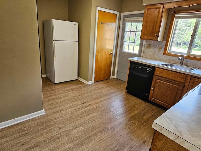 1363 Swain St, White Cloud, MI 49349 - kitchen with freestanding refrigerator, black dishwasher, light wood finished floors, brown cabinetry, and plenty of natural light
