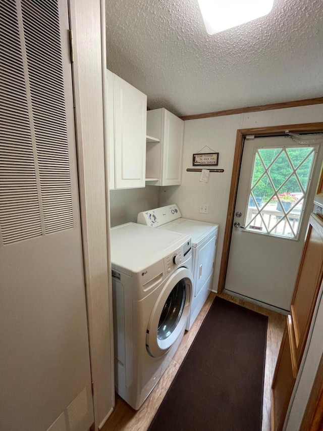 5814 N Trails End Dr, Irons, MI 49644 - laundry area with a heating unit, a textured ceiling, cabinet space, washer and clothes dryer, and wood finished floors