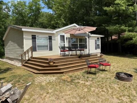 5814 N Trails End Dr, Irons, MI 49644 - rear view of house with a wooden deck, a lawn, and an outdoor fire pit