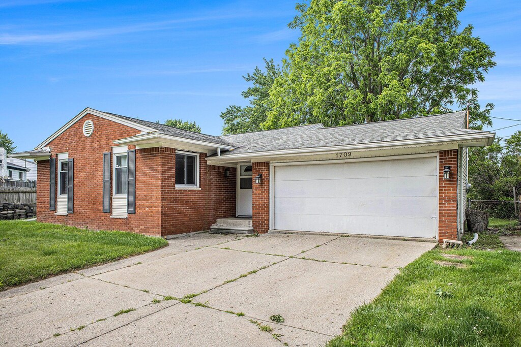 1709 Tuscany Ln, Holt, MI 48842 - view of front of home with brick siding, driveway, an attached garage, and roof with shingles