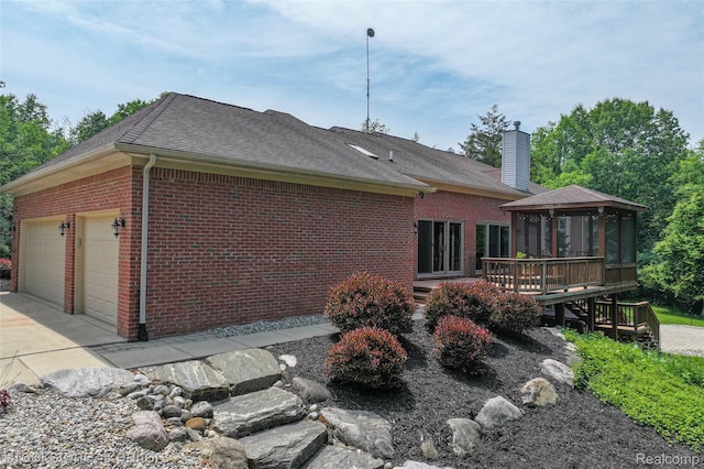 6439 Cohoctah Rd, Fenton, MI 48430 - view of home's exterior featuring a gazebo, brick siding, a chimney, roof with shingles, and a garage