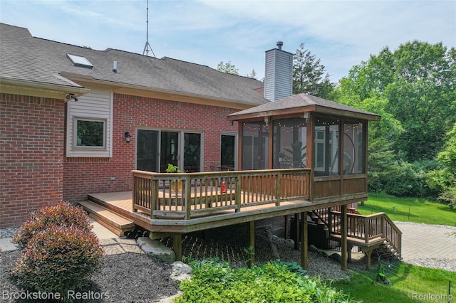 6439 Cohoctah Rd, Fenton, MI 48430 - back of property featuring a sunroom, a wooden deck, brick siding, a shingled roof, and a chimney
