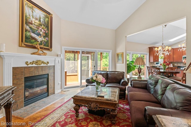 6439 Cohoctah Rd, Fenton, MI 48430 - living room with high vaulted ceiling, a chandelier, light wood-style flooring, and a tiled fireplace