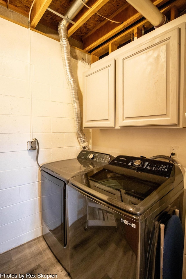 4585 W Arrowhead Dr, White Cloud, MI 49349 - laundry area featuring washing machine and dryer, wood finished floors, cabinet space, and concrete block wall